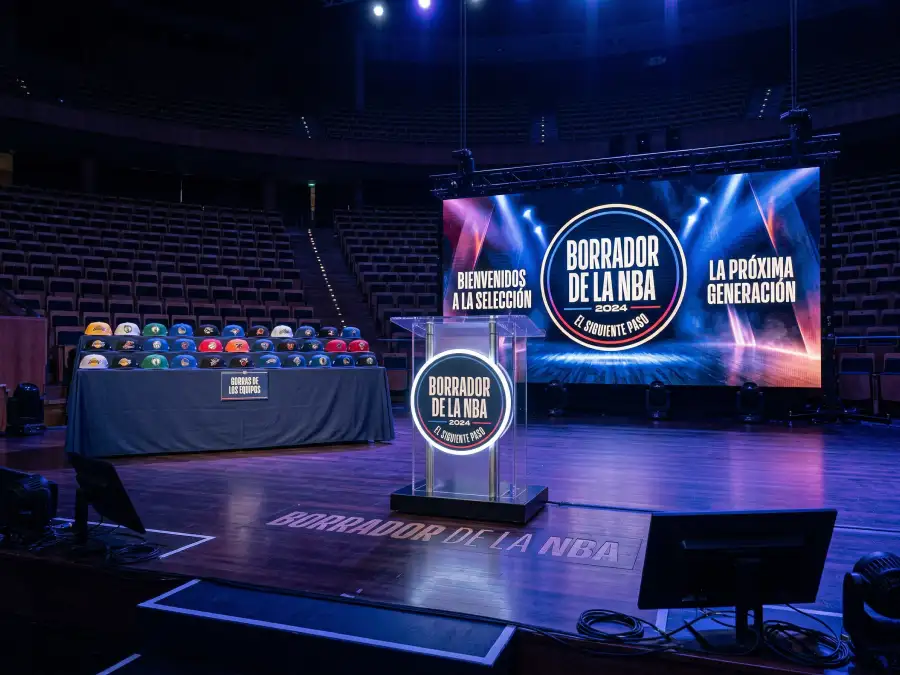 Escenario del NBA Draft con podio y gorras de equipos de baloncesto alineadas