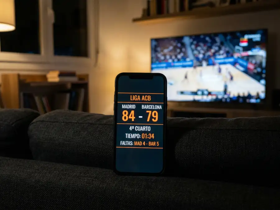 Apuestas NBA en directo: aficionado siguiendo un partido de baloncesto en vivo desde su móvil