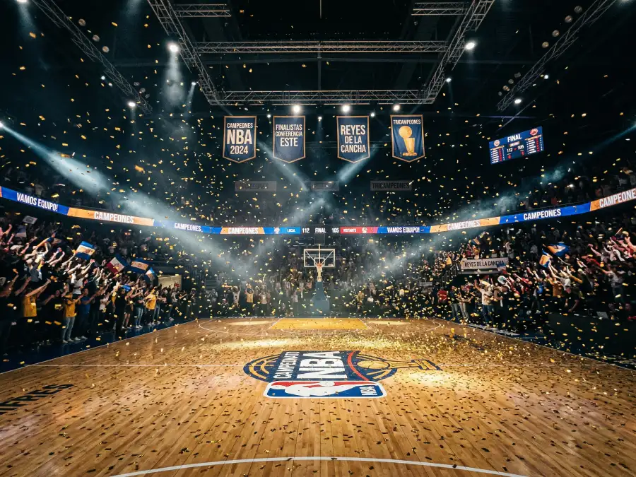 Cancha NBA durante un partido de playoffs con confeti dorado cayendo sobre la duela