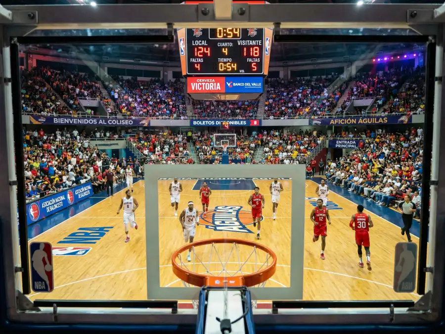 Marcador de partido NBA iluminado mostrando una puntuación total alta en un pabellón