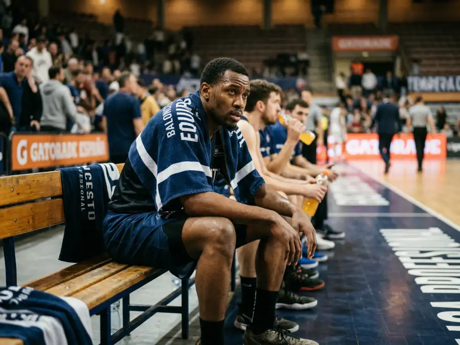 Jugador de baloncesto NBA sentado en el banquillo con expresión de fatiga tras un partido