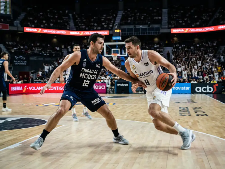 Dos jugadores de baloncesto NBA en un enfrentamiento defensivo durante un partido