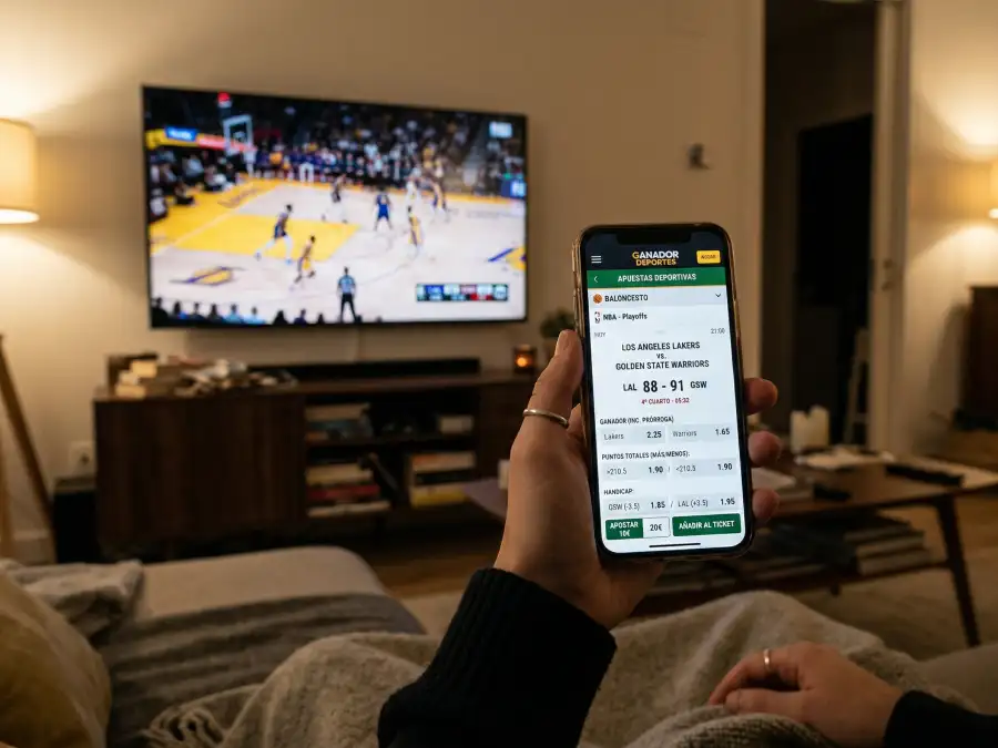 Teléfono móvil mostrando una aplicación de apuestas deportivas con un partido de baloncesto NBA