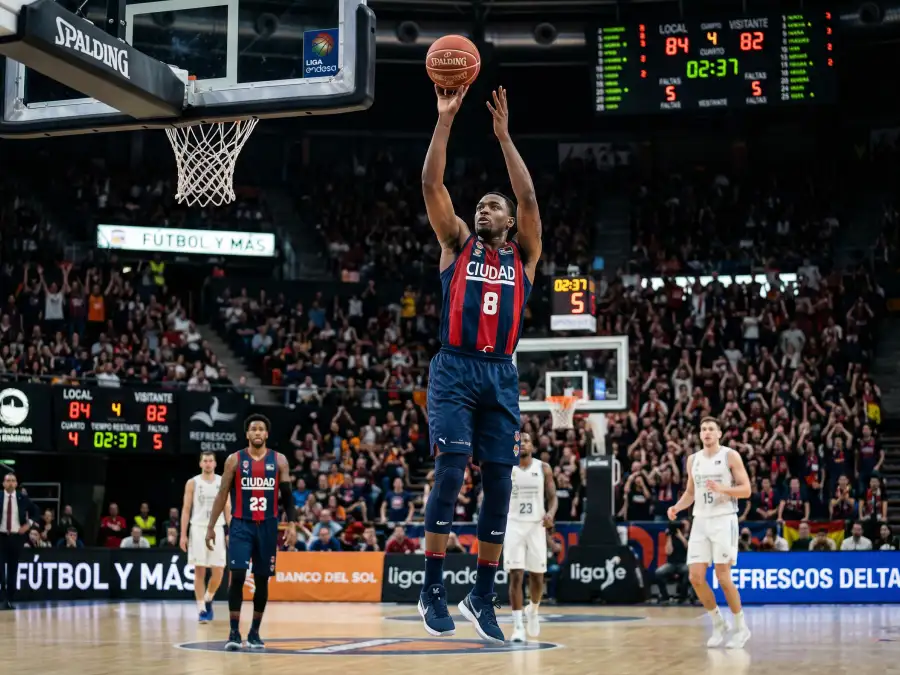 Jugador de baloncesto NBA lanzando a canasta durante un partido profesional